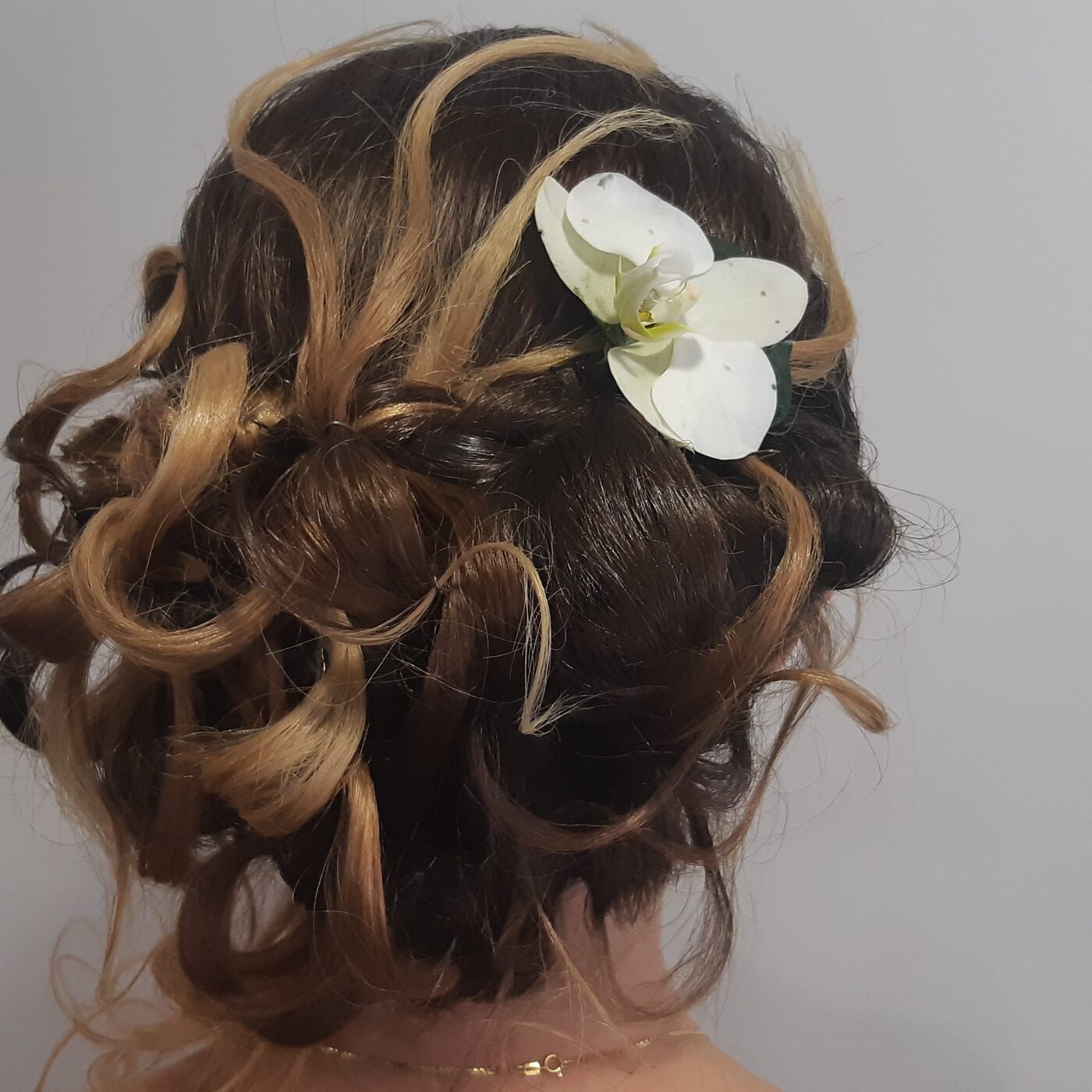 Chignon de mariage bouclé orné d'une orchidée blanche